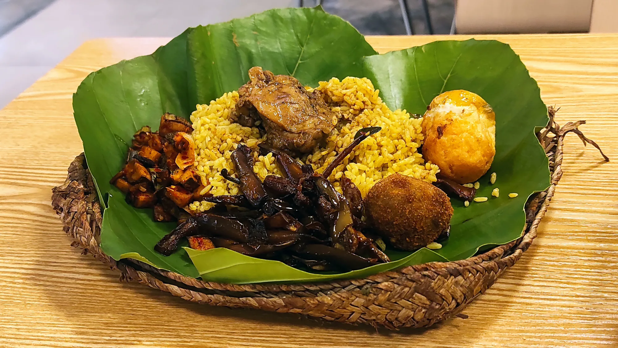 Lamprais served on a banana leaf: rice, curries, sambol and a boiled egg